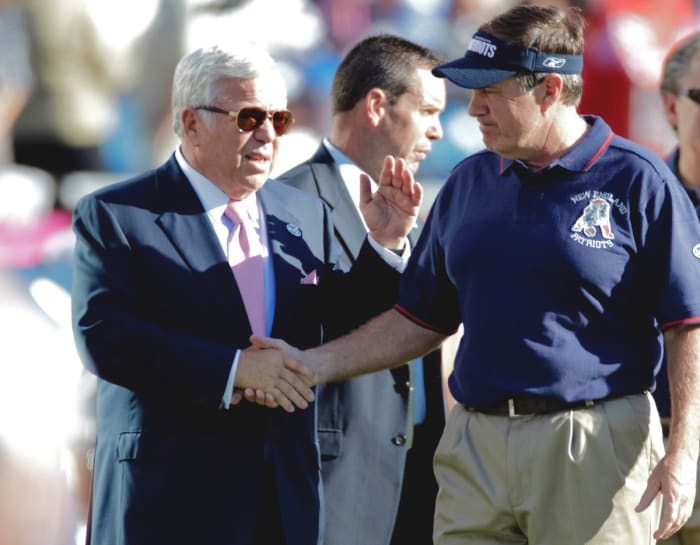 Robert Kraft shakes hands with Bill Belichick on the field.